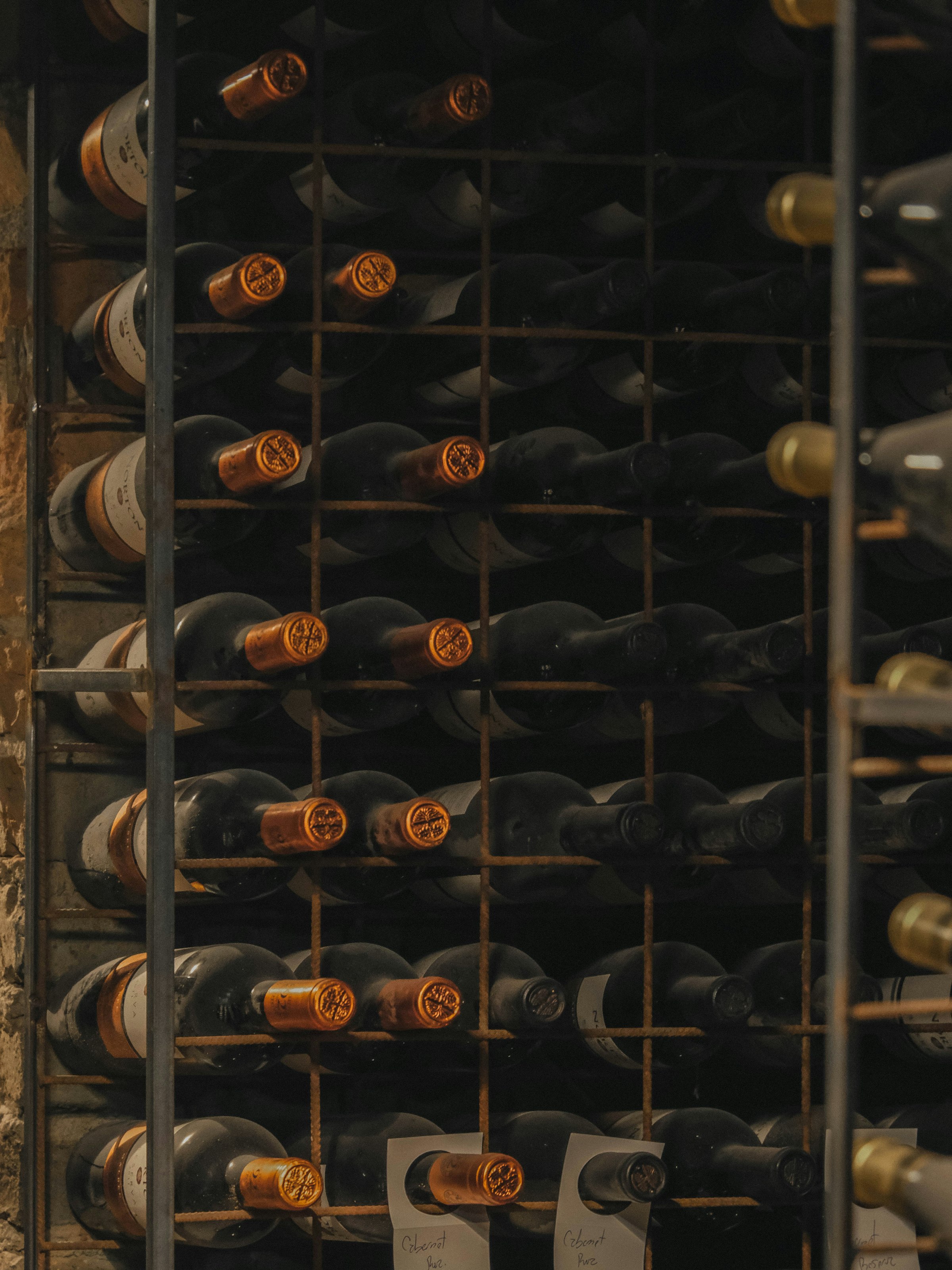 Vinske boce položene horizontalno na drvenom regalu — pravilan način čuvanja vina sa plutanim čepom